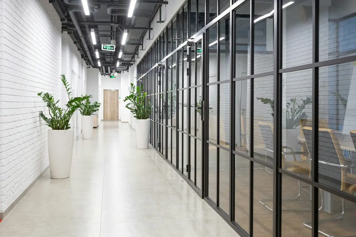 Pasillo de oficinas con mamparas de vidrio y perfiles negros